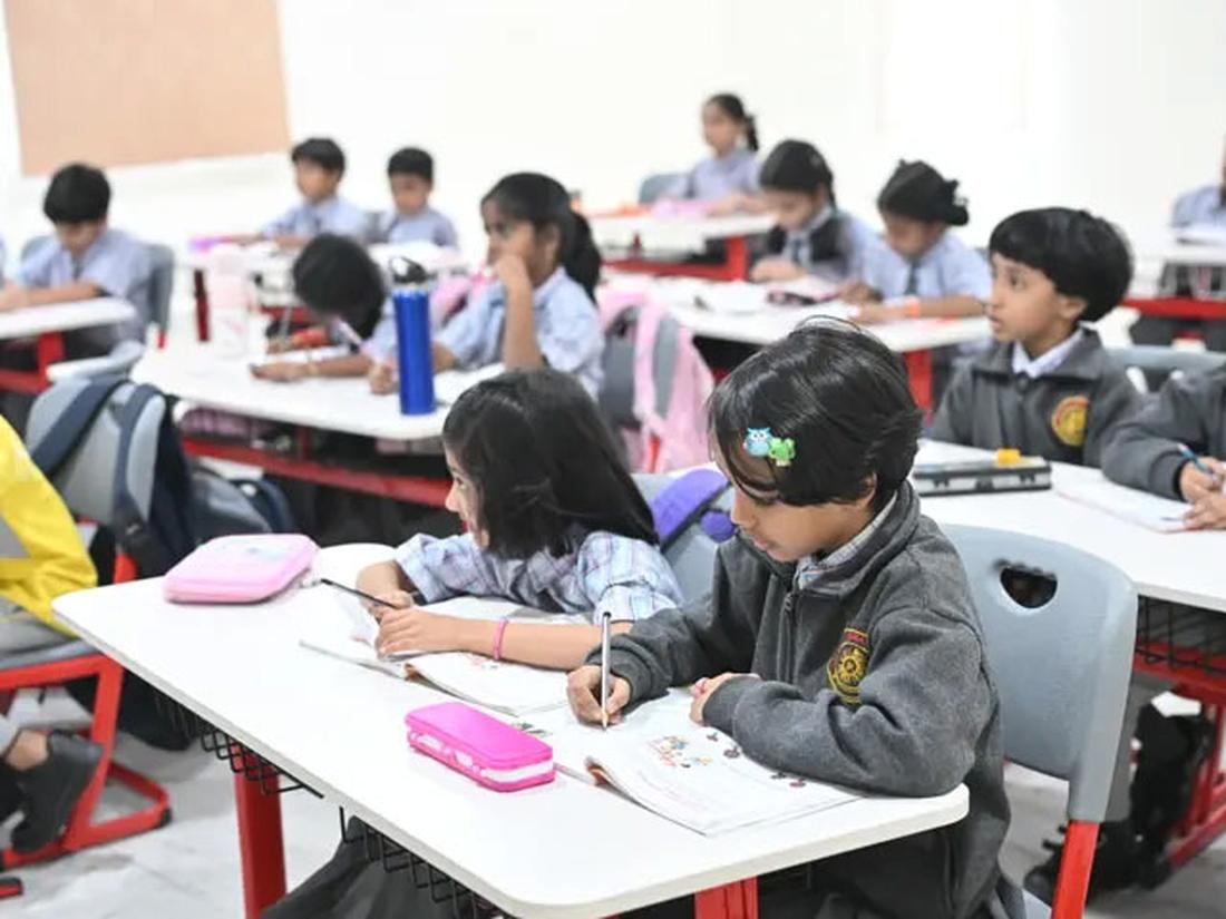 Primary students writing in notebooks at their desks