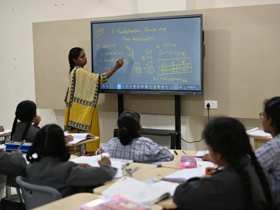 Teacher explaining a lesson on an interactive panel to middle school students